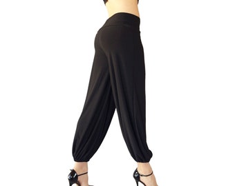 May include: Black, loose-fitting pants with a gathered elastic waistband. The pants are made of a soft, stretchy fabric and have a wide leg.