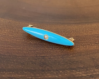 May include: A gold-toned brooch with a light blue enamel oval shape and a single pearl accent.