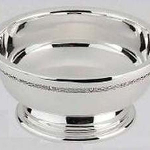 May include: A polished silver bowl with two decorative handles. The bowl has a patterned band around the rim and rests on a tiered base. The handles are adorned with Celtic knot designs.