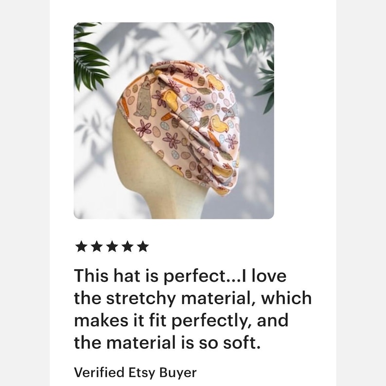 May include: A light pink turban-style hat featuring a repeating pattern of brown rabbits, yellow chicks, orange carrots, and colorful Easter eggs. The fabric has a gathered, twisted design at the top and is displayed on a neutral mannequin head.