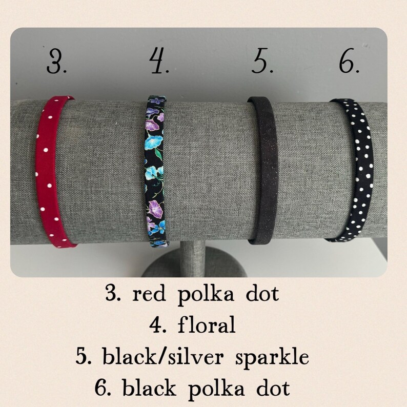 Puede incluir: Cuatro cintas para el pelo diferentes expuestas en un soporte. Las cintas para el pelo son rojas con lunares blancos, negras con estampado floral, negras con purpurina plateada y negras con lunares blancos.
