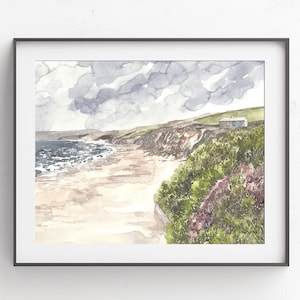 May include: Watercolor painting of a beach scene with a small house on a cliff overlooking the ocean. The sky is cloudy and the water is a light blue. The beach is sandy and there are green bushes in the foreground.