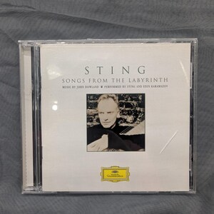 May include: A CD case for the album "Songs From The Labyrinth" by Sting. The cover displays a black and white image of Sting, with the album title and artist name. The CD is housed in a clear plastic case.