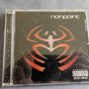 May include: A compact disc case featuring the album "Statement" by Nonpoint. The cover is black with an orange and red abstract design. The text "nonpoint" and "statement" are visible. A parental advisory warning is also present.