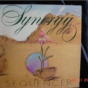 May include: Album cover for "Synergy" featuring a surreal landscape with a large flower and a broken pot. The word "Synergy" is in elegant script, and the title "Sequencer" is at the bottom. The date "JUL 11 2016" is also visible.