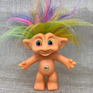 May include: A rainbow-haired troll doll with a jeweled belly button. The troll has large, colorful eyes and a friendly smile.