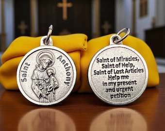 May include: Two silver Saint Anthony medals. One side depicts Saint Anthony holding a child, with the words "Saint Anthony" around the edge. The other side has the text "Saint of Miracles, Saint of Help, Saint of Lost Articles, Help me in my present and urgent petition."