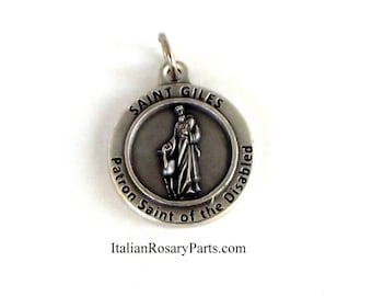 May include: Silver metal pendant with a depiction of Saint Giles, the patron saint of the disabled. The pendant features an image of Saint Giles with a lamb, and the words "Saint Giles Patron Saint of the Disabled" are inscribed around the edge.