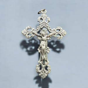 Pode incluir: Um pingente de prata em forma de crucifixo com um design ornamentado. A figura de Jesus Cristo &eacute; representada na cruz com a inscri&ccedil;&atilde;o "INRI" acima.