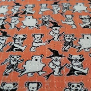 May include: A sheet of orange patterned paper with a repeating design of black and white bears in various Halloween costumes. The bears are wearing costumes such as a ghost, a witch, a skeleton, and a Frankenstein monster.