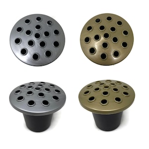 May include: Four flower frogs are shown. Two are silver and two are gold. Each has a circular top with holes for arranging flowers. The base of each frog is black. These frogs are designed to hold flowers in place.
