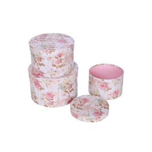 May include: A collection of four round gift boxes with a floral design. The boxes have a white base with pink and yellow roses and green foliage. One box has a pink interior.