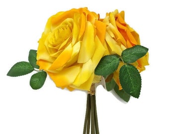 May include: A bouquet of yellow silk roses with green leaves and brown stems.