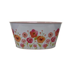 May include: A white metal planter with a floral design featuring orange and pink flowers. The planter has a light pink rim and a wide, oval shape. The flowers are arranged in a band around the planter.