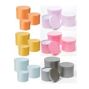 May include: Set of round cardboard gift boxes in various sizes and colours, including orange, yellow, pink, light blue, and grey. The boxes have lids and are ideal for presenting gifts.