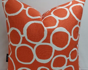 May include: Orange and white throw pillow with a geometric pattern of overlapping circles.