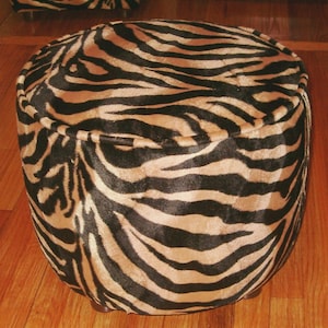 May include: A round, black and tan zebra print ottoman with a tufted top.
