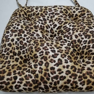 May include: A brown and tan leopard print chair cushion with a tufted design.