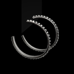 May include: A pair of silver hoop earrings with a beaded edge.