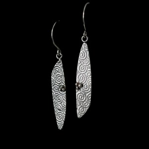 May include: A pair of silver dangle earrings with a swirl pattern and a small bead accent.
