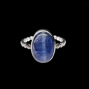May include: A silver ring with a blue oval gemstone. The ring has a beaded band.