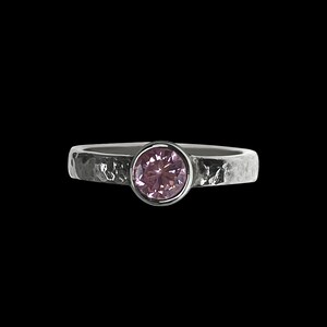 May include: A silver ring with a textured band and a pink gemstone.