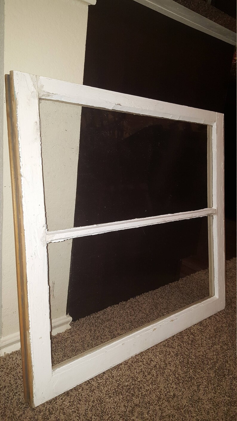 May include: White painted wood window frame with two panes of glass. The frame is slightly weathered and has a rustic look.
