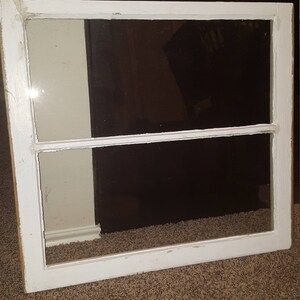 May include: A white painted wooden window frame with two panes of glass. The window is on a brown carpet.