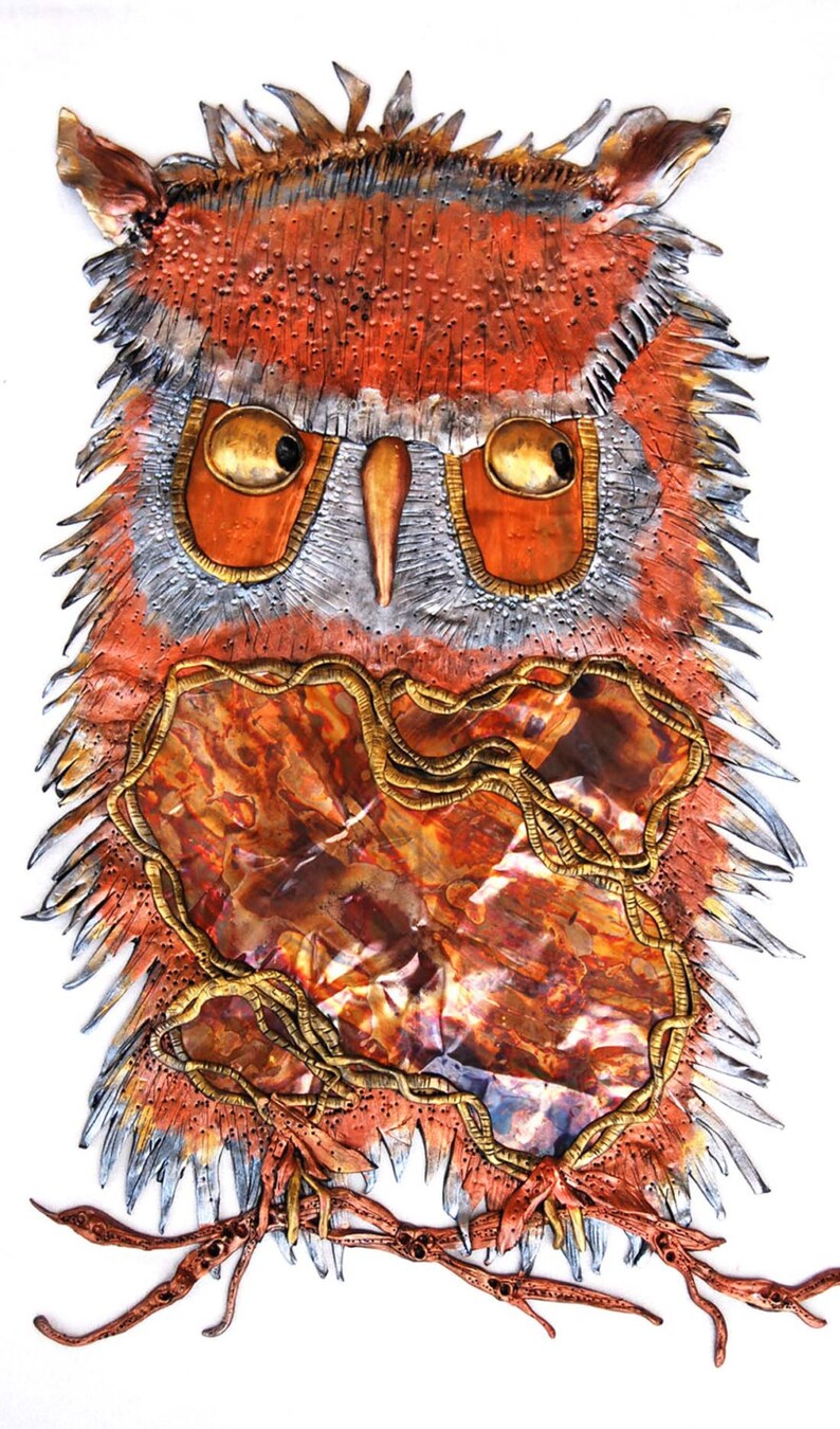 Op de afbeelding: Een metalen uilensculptuur met een textuur, oranje, bruin en gouden afwerking. De ogen van de uil zijn groot en rond, en zijn snavel is lang en puntig. De veren van de uil zijn gedetailleerd en realistisch.