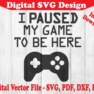 May include: Black and white digital design with the text "I paused my game to be here" and a video game controller graphic.  The design is on a white wood background.