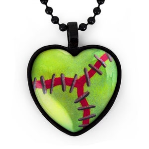 Pode incluir: Um colar de corrente preta com um pingente de cora&ccedil;&atilde;o verde. O pingente tem um design de beisebol vermelho costurado.