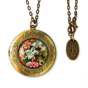May include: A gold locket necklace with a floral design. The locket has a round glass window with a colorful image of orchids. The necklace has a chain with a clasp and a small tag with the initials "JK".