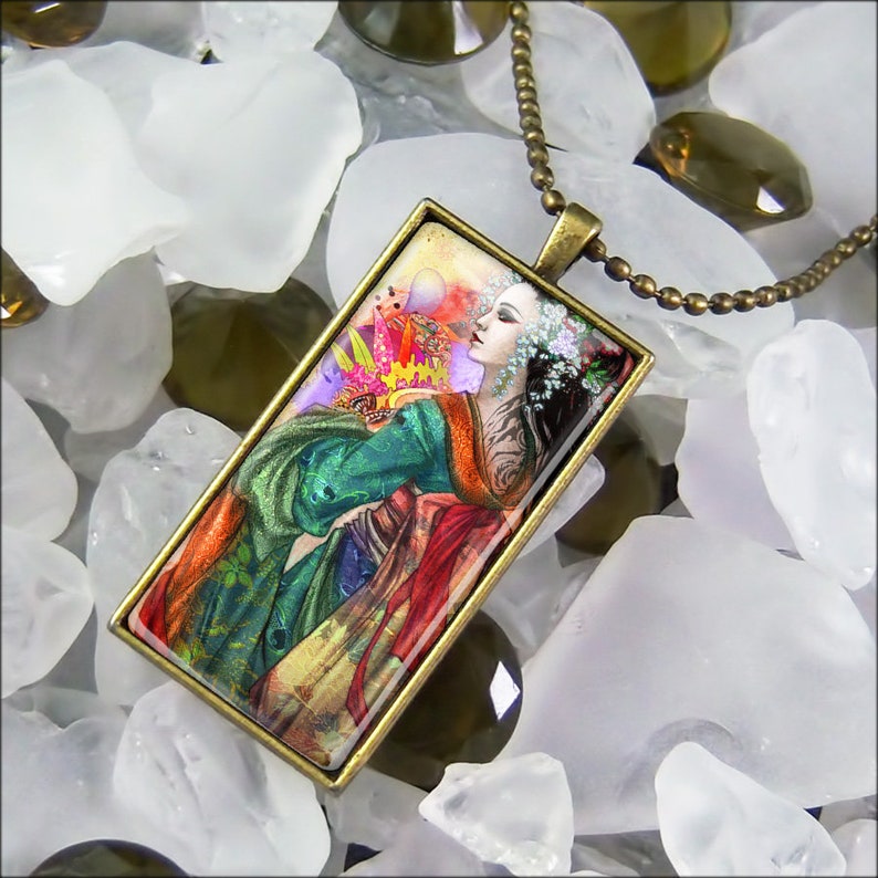 May include: A rectangular pendant necklace with a bronze-colored chain. The pendant features a colorful illustration of a woman in a green and red robe, with a floral headpiece. The background is a mix of white and green stones.