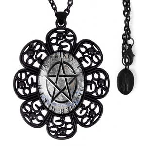May include: Black necklace with a large, ornate pendant featuring a silver pentagram on a black background. The pendant is shaped like a flower with intricate details. The necklace is made of a chain with a black finish.