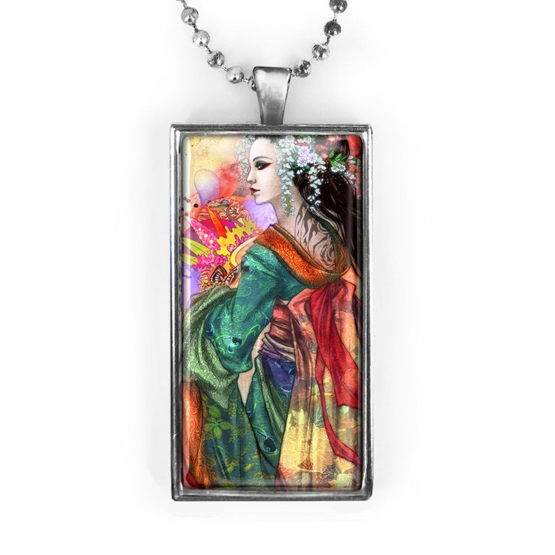 May include: A rectangular pendant with a silver-colored frame and a ball chain necklace. The pendant features a colorful illustration of a woman in a traditional Japanese kimono. The woman has dark hair and is adorned with flowers.