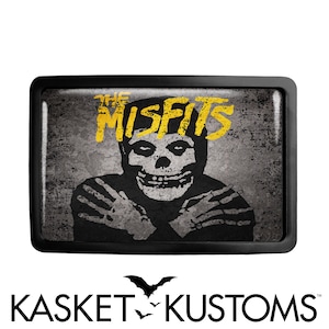 May include: A black belt buckle with a distressed gray and black image of a skull with the words "The Misfits" in yellow lettering.