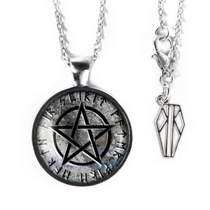 May include: A silver-toned necklace featuring a circular pendant with a black pentagram design and runes. The pendant has a distressed, textured appearance. A smaller coffin-shaped charm hangs from the clasp.