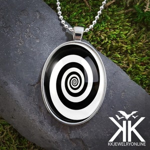 May include: A silver chain necklace with a round pendant featuring a black and white spiral design.