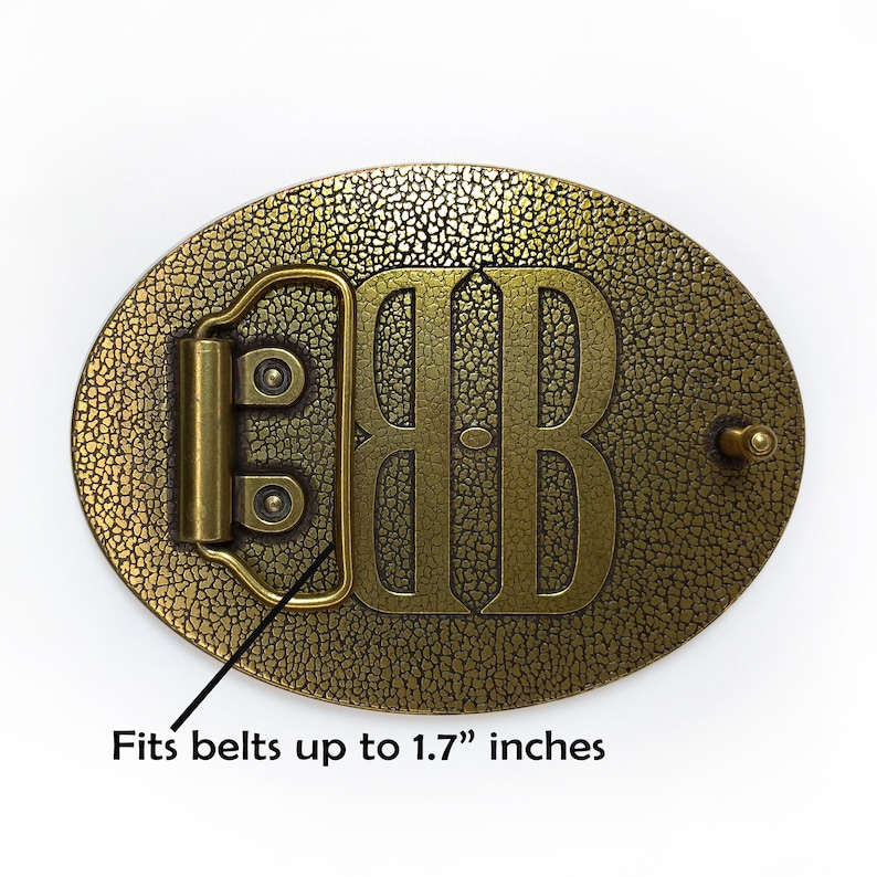May include: A gold-toned metal belt buckle with a textured surface and the initials "BB" engraved in the center. It fits belts up to 1.7 inches wide.