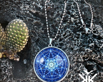 Puede incluir: Un collar de cadena de plata con un colgante redondo que presenta un diseño geométrico azul y blanco. El colgante tiene un borde plateado y un patrón detallado de líneas y formas.