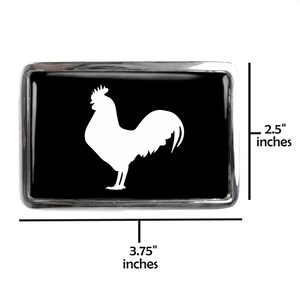 May include: A black and silver belt buckle with a white rooster silhouette. The buckle is 3.75 inches wide and 2.5 inches tall.