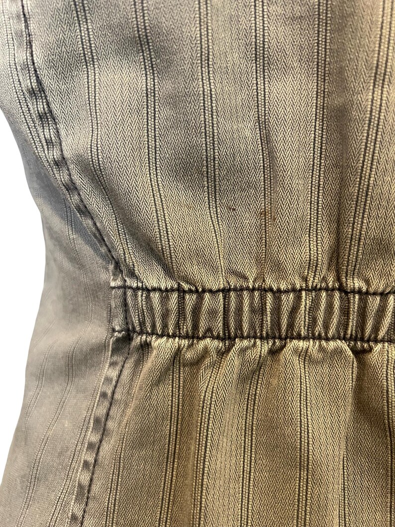 May include: A close-up of a brown and white striped fabric with a black elastic band at the waist.
