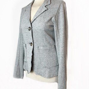 Op de afbeelding: Een grijze blazer met een reverskraag, drie knopen en twee zakken. De blazer heeft een licht verweerde look.