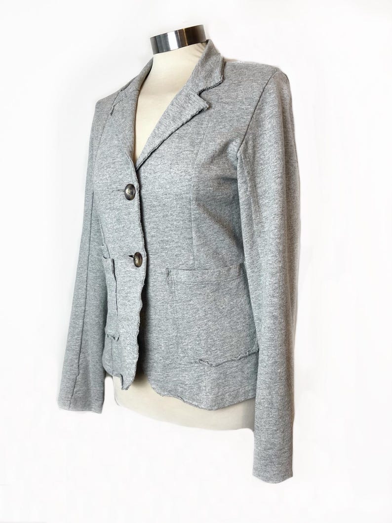 Op de afbeelding: Een grijze blazer met een reverskraag, drie knopen en twee zakken. De blazer heeft een licht verweerde look.