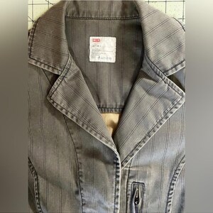 May include: A gray striped jacket with a zipper closure and a label that reads "DENIM" on the front.