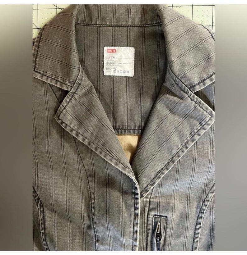 May include: A gray striped jacket with a zipper closure and a label that reads "DENIM" on the front.