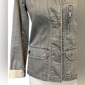 May include: A gray striped denim jacket with a zipper closure and two flap pockets. The jacket has a slightly fitted silhouette and a collar.