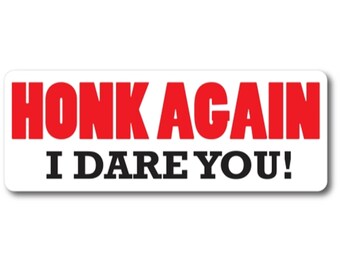 May include: A rectangular bumper sticker with a white background. The text HONK AGAIN is printed in large, bold red capital letters. Below this, the text I DARE YOU! is printed in smaller, bold black capital letters.