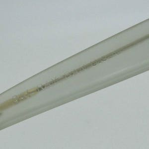 May include: Close-up of a clear eyeglass arm with the text "BAL RAY BRAZIL U.S.A." etched into the plastic. The arm is angled, showing the hinge and a portion of the frame.