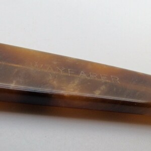 May include: Close-up of a Wayfarer style eyeglass frame in a tortoiseshell pattern. The frame is a warm brown color with a slight gradient. The word "WAYFARER" is etched into the frame.